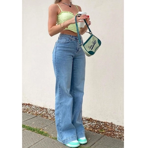 Détail d'un jean taille haute à jambes larges bleu clair avec chaîne de taille à cœur