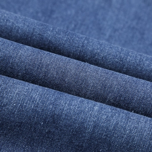 Détail en gros plan de la texture du denim bleu et du tissage sergé sur le pantalon
