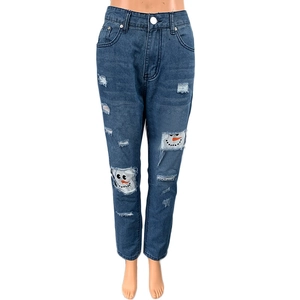 Detailed view of ripped blue jeans featuring festive snowman print patches inside the holes