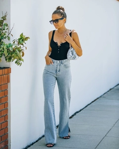 Detail of high waisted light blue flare jeans paired with a black ribbed button vest
