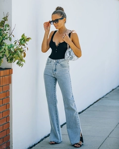 Detail of high waist flared jeans with side slit hem paired with a black ribbed tank top