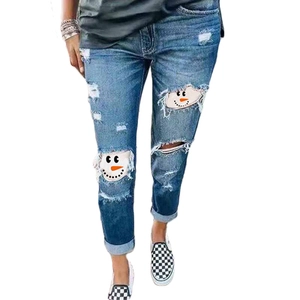 Distressed blue stretch jeans featuring snowman print patches in ripped denim holes