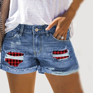 Close-up of distressed blue denim shorts featuring red plaid patches and frayed edges