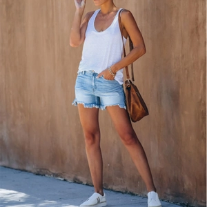 Women's white U-neck tank top and light blue distressed denim shorts with frayed hems