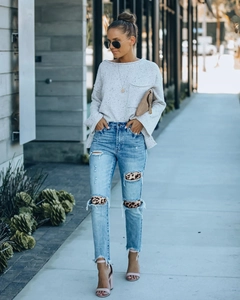Dettaglio di jeans a vita alta con toppe leopardate nelle aree strappate del denim