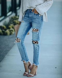 Dettaglio di jeans blu strappati con toppe leopardate e orli sfrangiati da donna