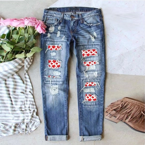 Slim fit blue distressed jeans with red and white heart print patches and rolled cuffs