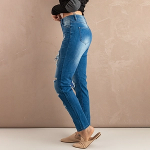 Close-up of light blue washed denim jeans with distressed ripped holes and cat whiskers