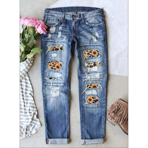 Close-up of distressed skinny jeans with sunflower and leopard print patches on fabric