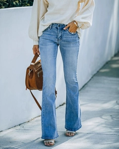 Detail of light blue high waist flare jeans with vintage wash effect and slim fit design