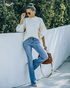Street style view of light blue flared jeans paired with a cream puff-sleeve knit sweater