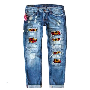 Women's ripped flare jeans with daisy patches and red plaid lining in washed blue