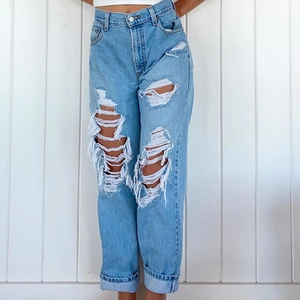 Close-up of high-waist light blue jeans featuring ripped knee details and cuffed hems