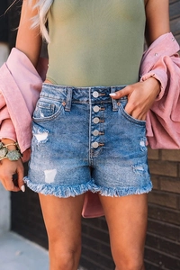 Detailed close-up of high-waisted denim shorts featuring button fly and frayed hem edges