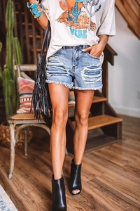 Détail de la texture vieillie déchirée et ourlet effiloché sur short en jean bleu
