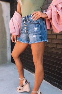 Detail view of high-waisted denim shorts featuring five-button fly and frayed raw hem edges