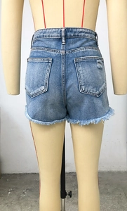 Détail du short en jean bleu clair avec ourlets effilochés et poches à effet usé
