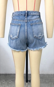 Detail of light blue high waist denim shorts featuring ripped back pockets and frayed hems