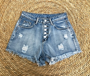 Close-up of high-waisted denim shorts with button fly and distressed frayed hem detailing