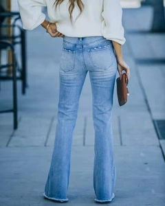 Détail de jean flare taille haute bleu clair avec ourlet brut et poches arrière usées
