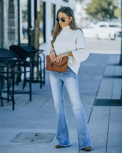 Détail d'un jean évasé taille haute à ourlet effiloché avec un pull en maille blanc