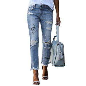 Women's light blue distressed skinny jeans featuring skull prints and ripped details