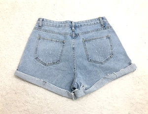 Détail arrière du short en jean bleu clair avec ourlets repliés et bords effilochés
