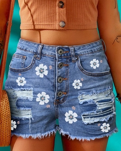 Detail of high waist denim shorts with daisy print, ripped holes and multi-button fly