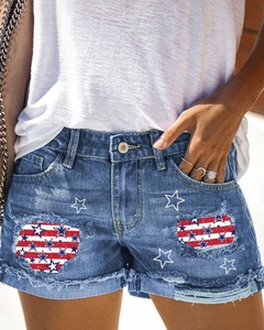 Detalle de los shorts de mezclilla desgastados con parches de bandera y estrellas