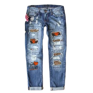 Women's baggy blue denim jeans with distressed holes and leopard print patches