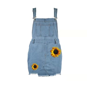 Women's light blue denim overall dress with sunflower embroidery and frayed hem detail