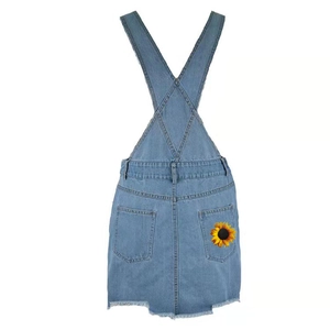 Women's light blue denim overall dress with sunflower print and frayed hem detail