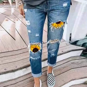 Detail der Destroyed-Jeans mit Sonnenblumen- und Leopardenmuster-Patches auf Denim