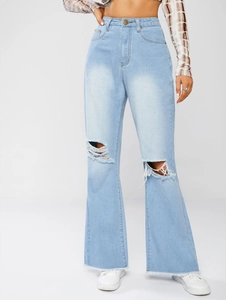 Detail view of high-waisted light blue denim jeans with ripped knees and raw hem