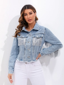 Dettaglio frange argentate e orlo sfrangiato su giacca di jeans lavaggio chiaro