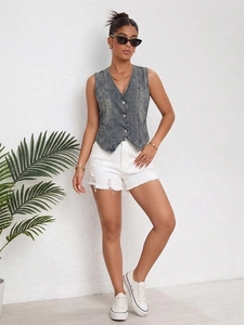 Detail of dark gray washed denim vest with V-neckline and distressed white denim shorts
