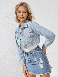Detail of light blue denim skirt featuring distressed ripped holes and raw frayed hemline