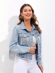 Dettaglio delle frange argentate su una giacca di jeans corta azzurro chiaro