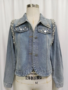 Détail de veste en jean bleu clair avec broderie de perles et de billes métalliques au col