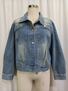 Detail view of light wash denim jacket with button flap pockets and classic pointed collar