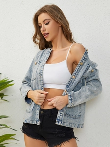 Detail of light blue denim jacket with gold buttons and high-waisted frayed black shorts