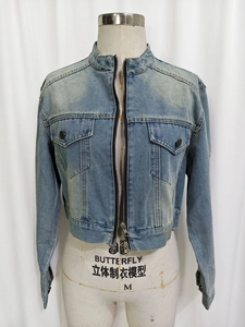 Detail view of light blue denim jacket with stand collar, zipper and utility chest pockets