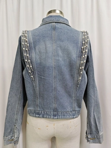 Détail des perles de luxe et ornements argentés sur le dos d'une veste en jean bleu clair