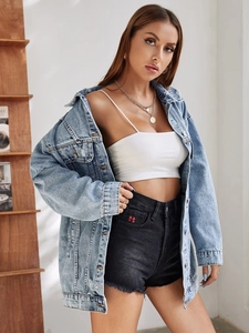 Détail d'une veste en jean délavée avec un short brodé d'un trèfle à quatre feuilles