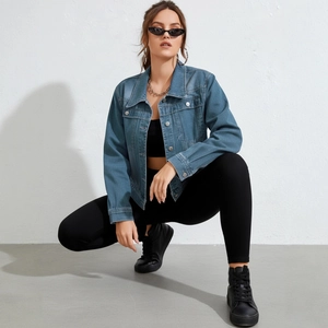 Women's light blue distressed denim jacket paired with black leggings and trendy accessories