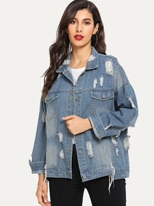 Detail of distressed blue denim jacket featuring shredded holes and frayed edges