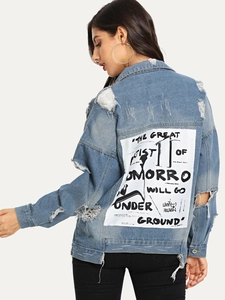 Close-up of light blue distressed denim jacket featuring artistic slogan back patch