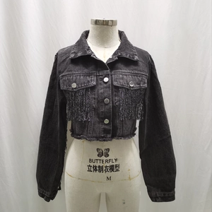 Dettaglio giacca di jeans grigio scuro con frange metalliche e bordo a taglio vivo