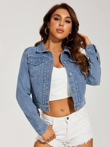 Detail of light blue washed denim jacket featuring classic collar and chest pocket texture