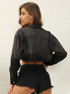 Dettaglio della giacca in denim nero cropped con orlo a vivo e shorts in denim strappati